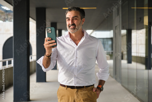 Businessman taking a break while using phone outdoors with optimism