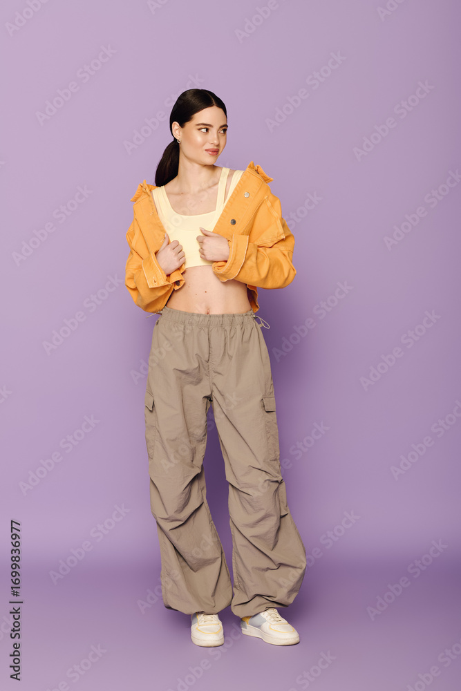 Fototapeta premium A beautiful young woman showcases her fashion sense with a bright orange jacket and relaxed pants.