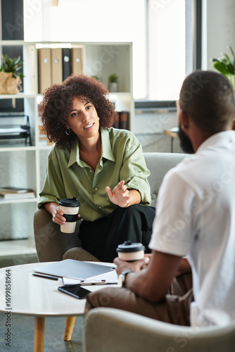 Modern office job interview between a young woman and man over coffee in an inviting space