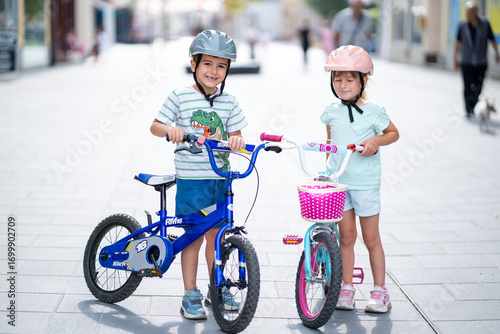 Two confident youngsters enjoy a bike ride in the city, showcasing their friendship and joy. The image highlights health and the importance of safety measures like wearing helmets. 