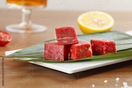 Fresh Diced Raw Beef Cubes on Banana Leaf with Lemon and Pomegranate