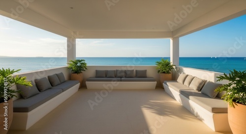 A bright outdoor terrace with white built-in seating grey cushions and potted plants overlooks a calm blue ocean under a clear sky with distant land and sailboats