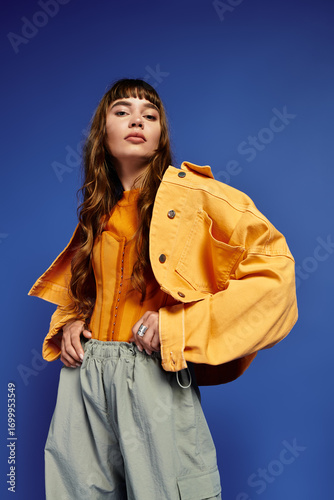 Canvastavla Stylish young woman showcases vibrant fashion against a bold blue backdrop