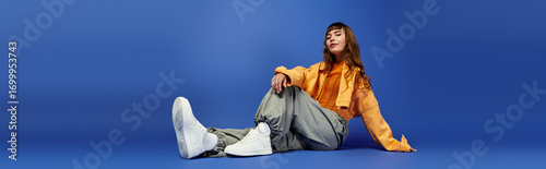 Photography Fashionable young woman poses stylishly against a vibrant blue backdrop with a c
