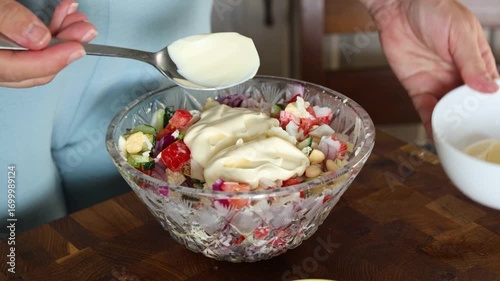 Preparing a salad in the home kitchen. Pregnant girl seasons chopped salad with mayonnaise and mixes