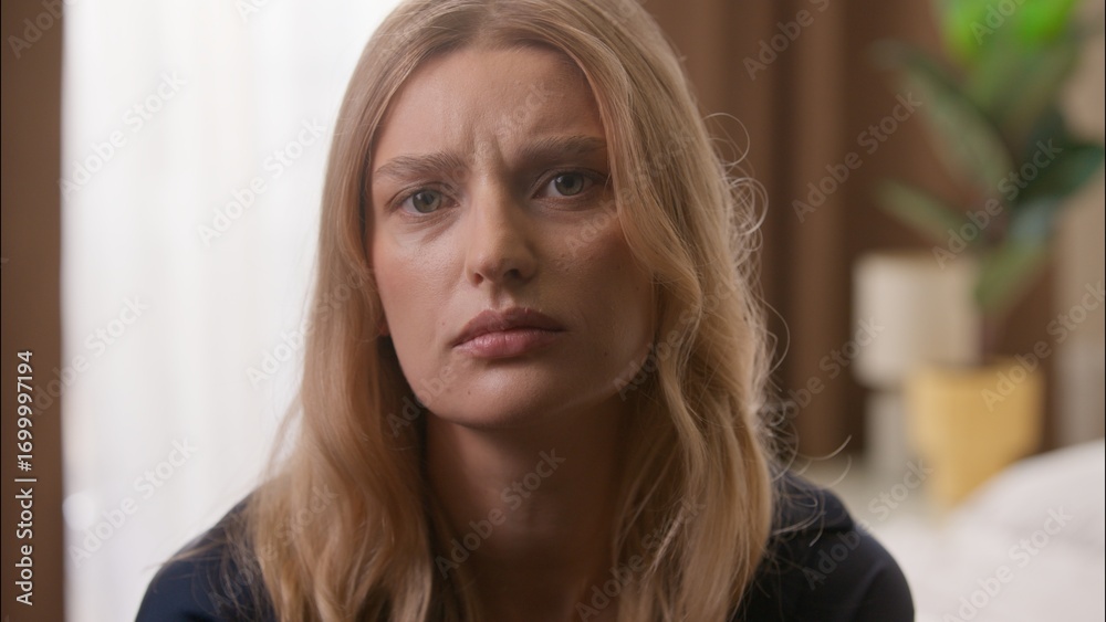 Fototapeta premium Worried Caucasian woman girl looking at camera feeling stressed at home upset adult female suffer anxiety problem morning disappointed frustrated face close up bedroom lady posing depression apartment