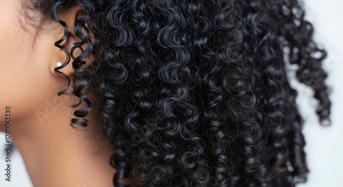 Closeup of dark curly hair and an ear with a pearl earring