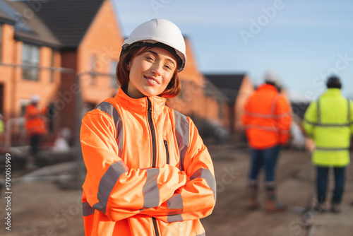 Portrait of Young female Construction works superviser overseeing building site activities  during sunny day while holding project files and wearing safety gear