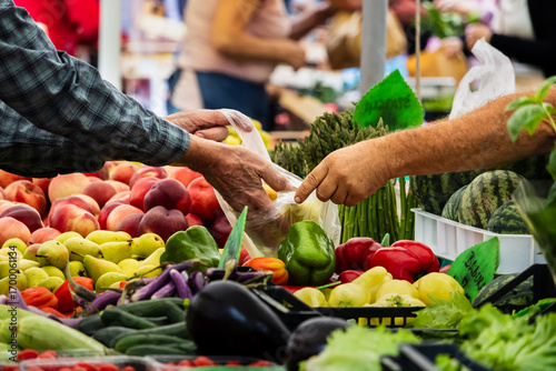 woman buying fruits, Hands exchanging produce at busy farmers' market, fresh vegetables displayed