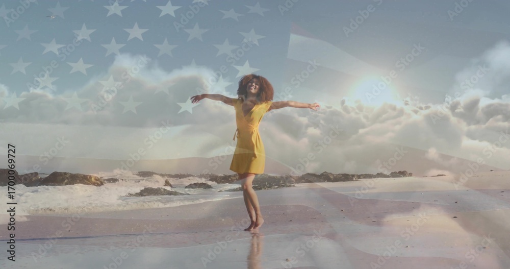 Fototapeta premium Dancing barefoot woman in yellow dress twirling on wet sand beach, with faint American flag overlay