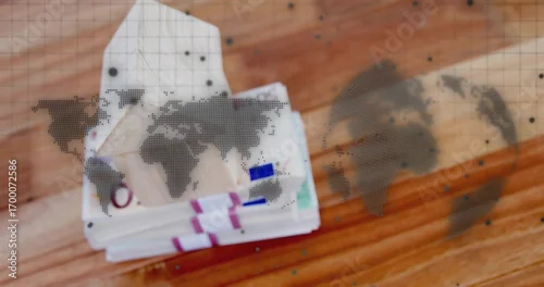Obraz Displaying stacks of euro banknotes with colored straps on wood tabletop, showing world map overlay
