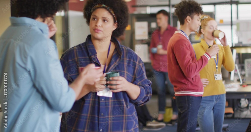 Φωτογραφία Adult woman wearing plaid shirt holding coffee mug listening to coworker in brea