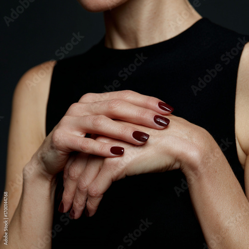 Woman with dark red manicure holding hands.