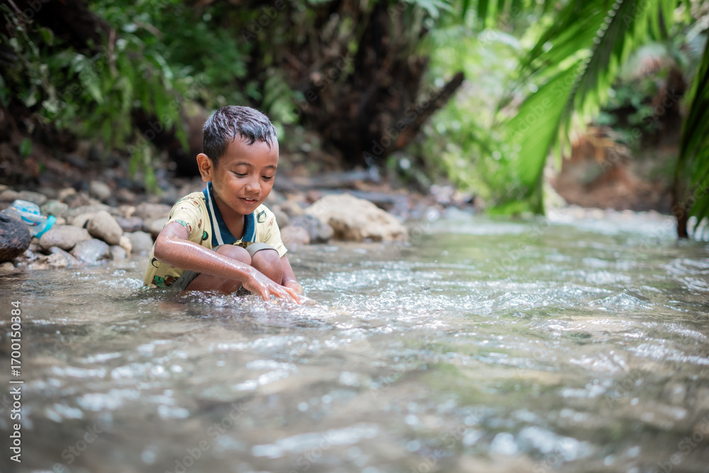 Fototapeta premium Asian boy is playing in the river