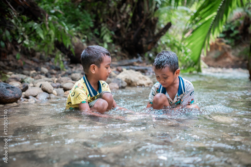 Asian twin boys are playing in the river