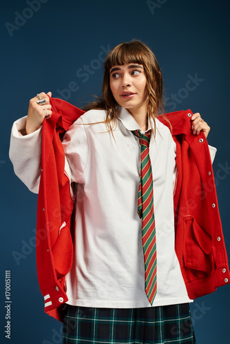 Canvas Print Young female student joyfully puts on a vibrant jacket with a playful expression