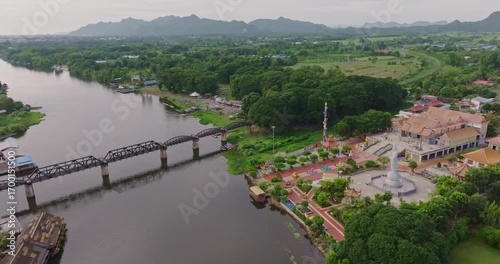 Aerial View of River Kwai and Iconic Bridge in Kanchanaburi Surrounded by Lush Greenery and Distant Mountains