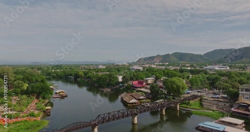 Scenic Aerial View of River Kwais Iconic Bridge in Kanchanaburi Surrounded by Lush Greenery and Distant Hills and Mountains