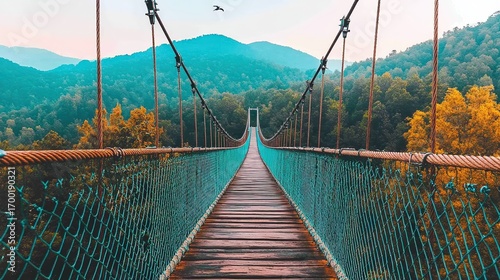 A scenic suspension bridge stretches across a lush valley, framed by vibrant autumn foliage and distant mountains, This image can be used for travel blogs, nature websites