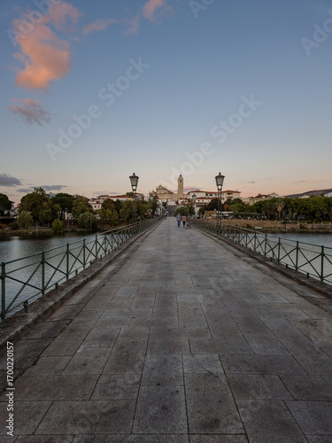 The historic granite Old Bridge crosses the Tua River in Mirandela, Portugal with the cityscape and iconic tower behind. This scenic pedestrian landmark blends heritage and beauty in northern Portugal