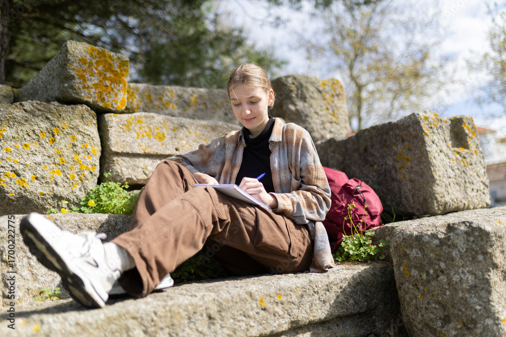 Fototapeta premium Young archaeologist writing notes outdoors on ancient ruins