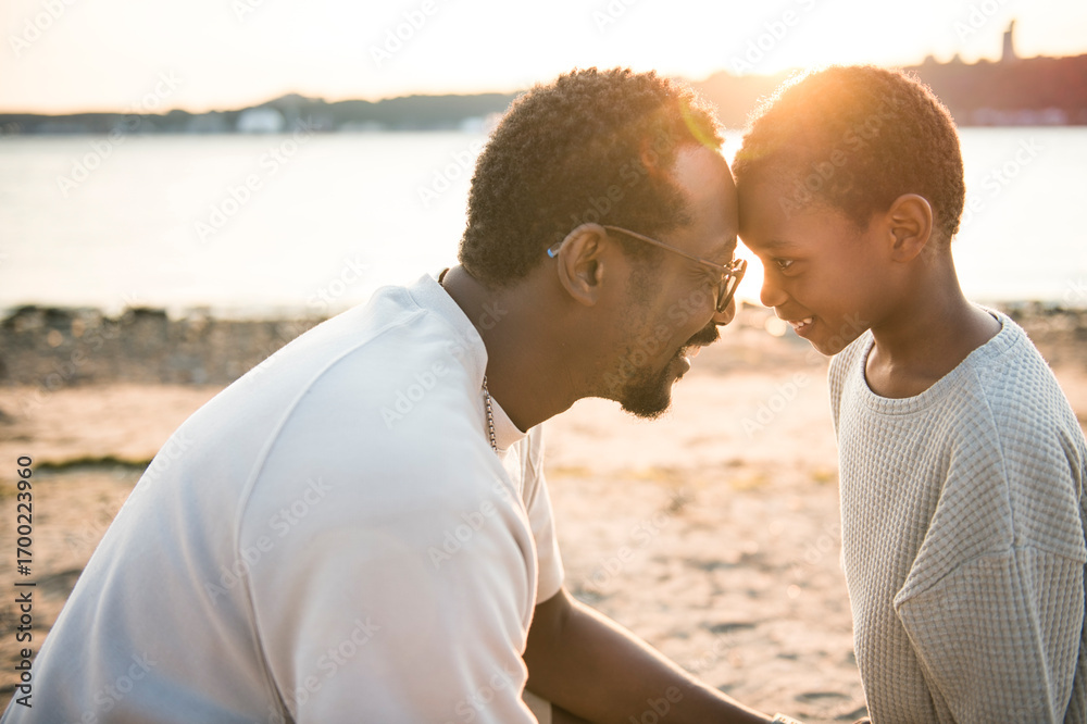 Obraz premium Cheerful black american father and son against beautiful seascape