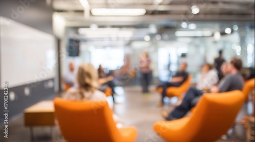 A blurred image of a modern meeting space with people seated and engaging in discussion, showcasing a collaborative environment.