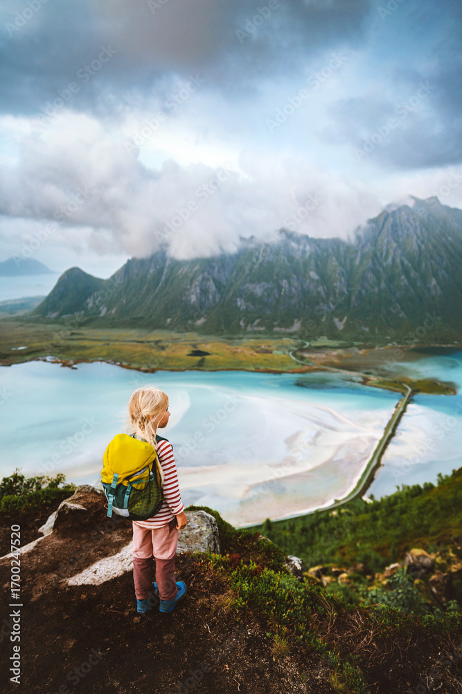 Naklejka premium Child traveling in Norway hike in Lofoten islands active family vacations outdoor healthy lifestyle 5 years old kid girl backpacker enjoying sea aerial view from Matmora mountain