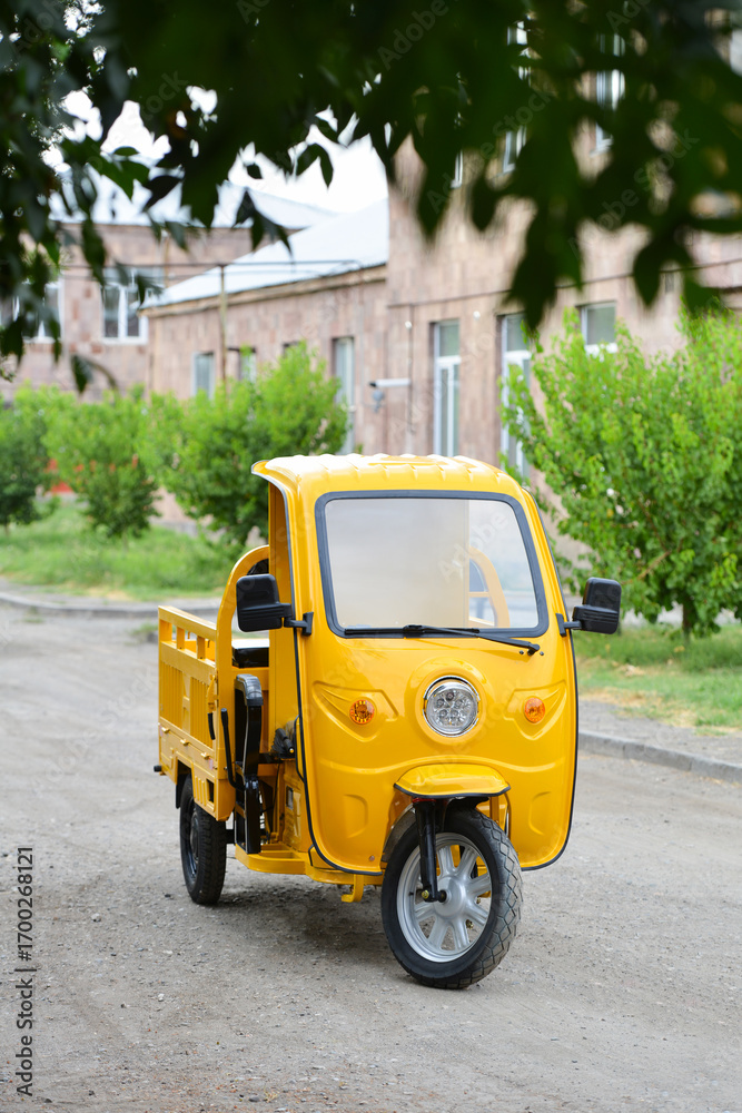 Obraz premium Yellow electric cargo tuk tuk in the park