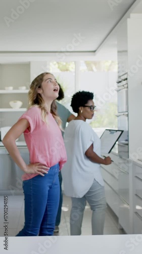 Vertical video: Entering kitchen, Diverse trio touring oven, signing paperwork and celebrating