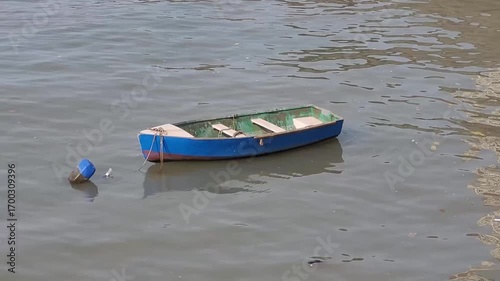 A very small, empty wooden boat gently floating on calm water, creating a serene and peaceful view