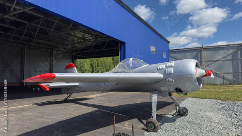 A Soviet sports plane stands near a hangar