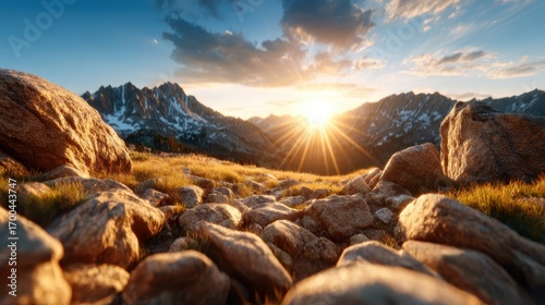 A stunning sunset illuminates a rugged mountain landscape, casting warm hues over the rocky foreground, symbolizing nature's beauty and serenity in the wilderness.