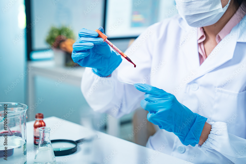 Fototapeta premium Close-up of a scientist in protective gloves placing a drop of blood on a glass slide for microscopic analysis, symbolizing healthcare diagnostics, medical research, and scientific precision.