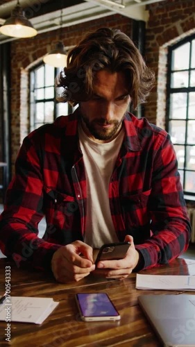 A man is sitting at a table with a cell phone in his hand