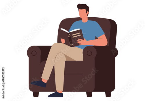 A seated man in a brown armchair reads a book He is wearing blue shirt beige pants and dark shoes