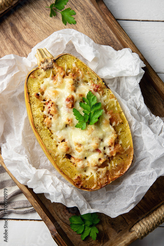 Spaghetti squash or vegetable spaghetti stuffed with minced meat and cheese, served in its shell. Homemade dish on a rustic wooden background.