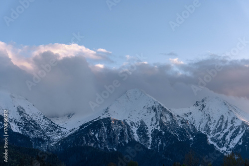 Fototapeta Naklejka Na Ścianę i Meble -  snow covered mountains tatry poland with clouds around and big pine trees