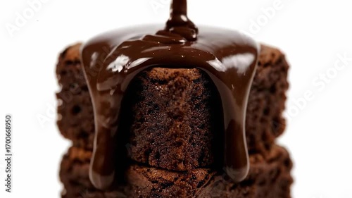 Close-up of melting chocolate dripping over stacked cubes of brownie, glossy texture, isolated on clean white background
