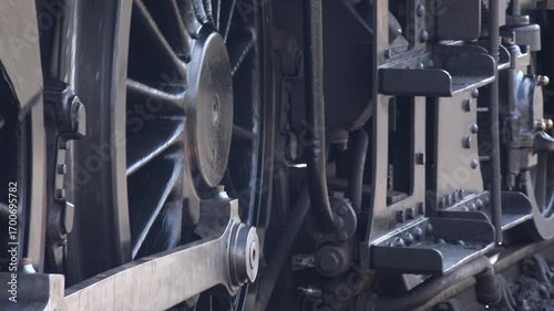 Close up of steam train wheels turning as locomotive moves away from a station as tourists take heritage transport in England UK 4K