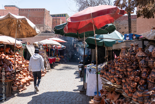 Man strolls through a vibrant moroccan market in marrakech, browsing stalls filled with colorful pottery and local crafts