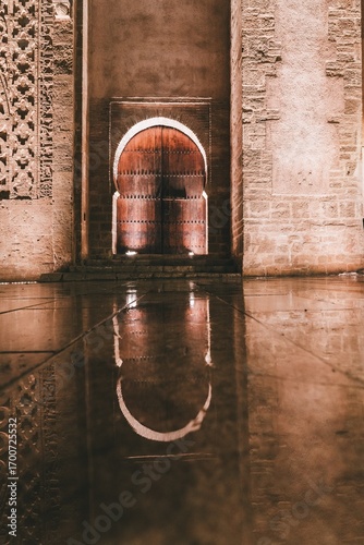light from an Arabic arch reflected on the wet ground