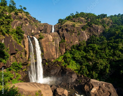 Waterfall cascading down rocky cliffs into lush forest