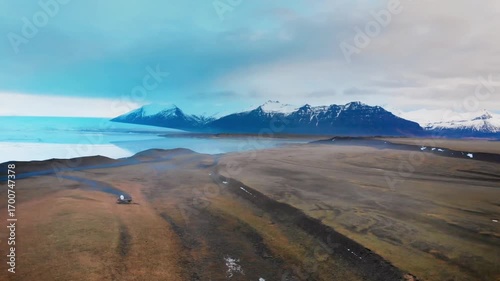 Aerial view of a vast glacial landscape with mountains and cloudy blue sky