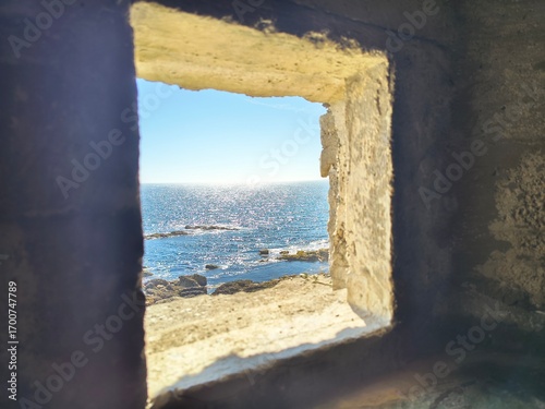 window in stone wall looking into sea in Cornwall