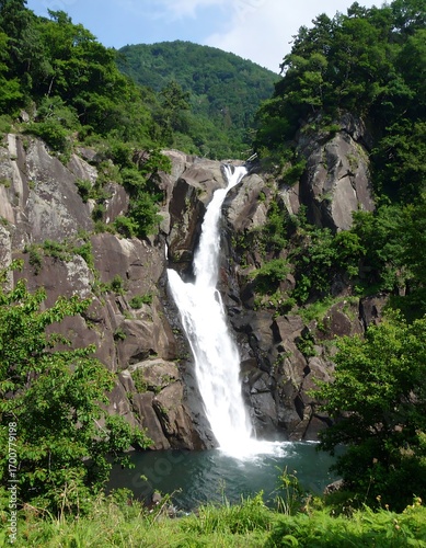 Waterfall cascading into a pool surrounded by lush green mountains