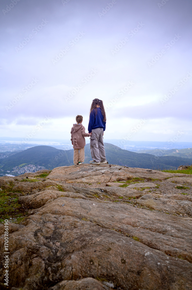 Obraz premium Two girls or sisters holding hands on the top of a mountain. Bergen, Norway,2025