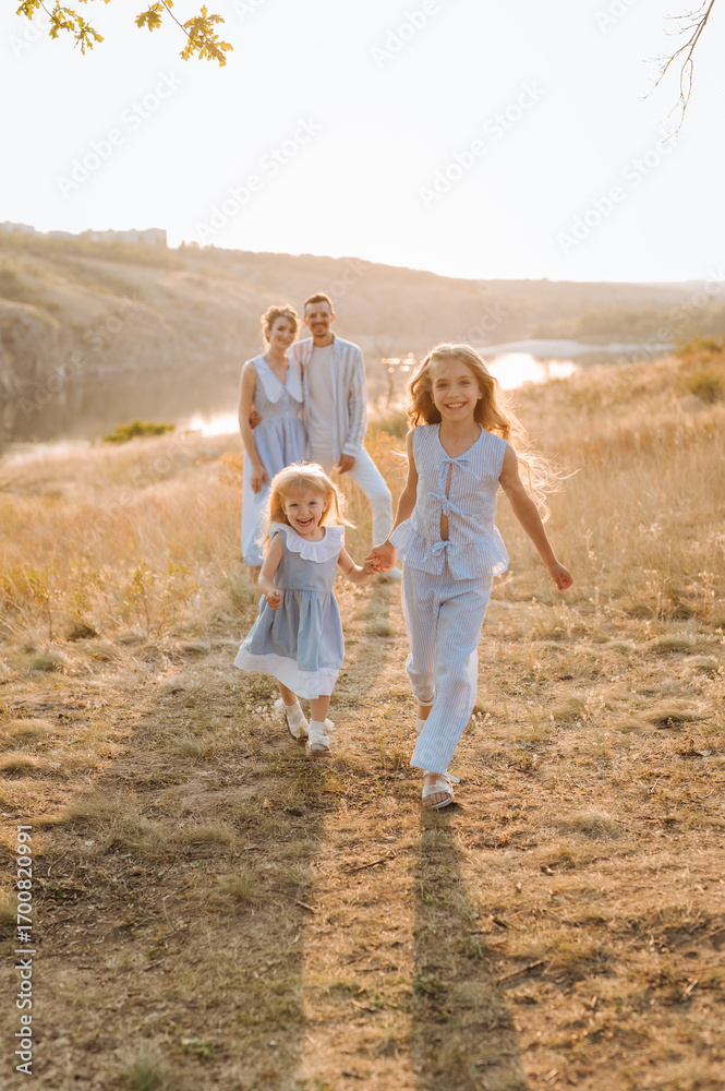 Fototapeta premium happy family having fun with two children in blue clothes on nature