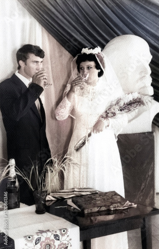 Lozovaya, UkrSSR, USSR - circa 1980: Vintage portrait of a bride and groom drinking champagne and eating candies at a registry office. Retro photo