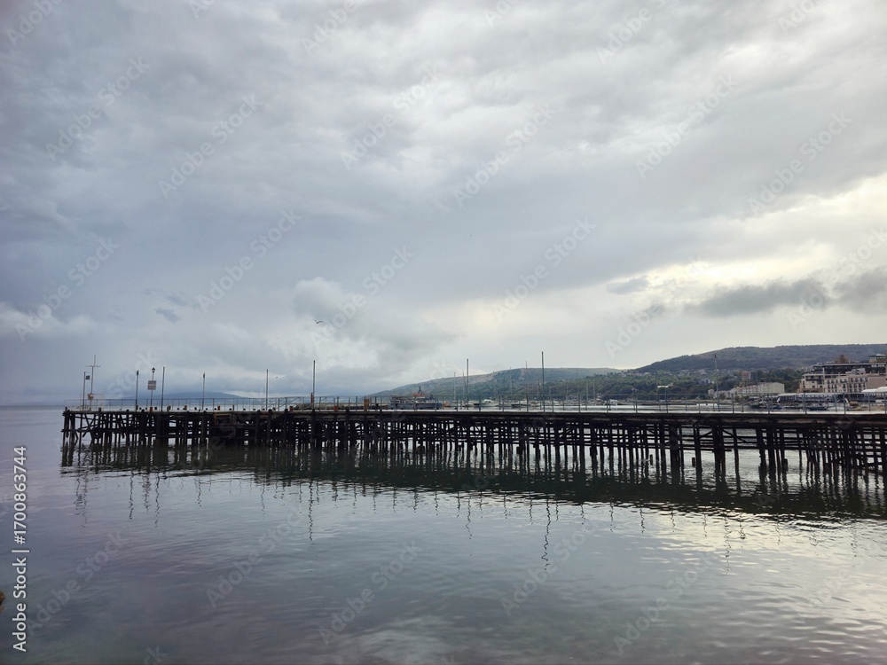 Naklejka premium Long wooden pier under cloudy sky